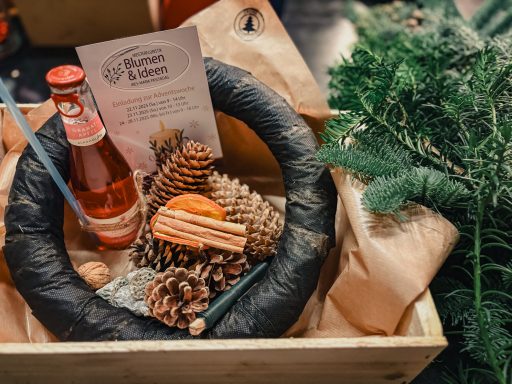 Adventskranz Workshop Weihnachtlicher Geschenkkorb mit Tannenzweigen, Zapfen und Getränkevariationen.