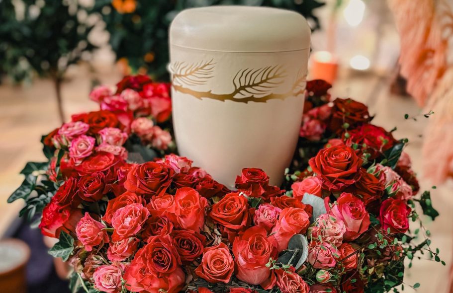 Dekorative Keramikhäuser, Blumen in Glasvasen, Schalen und Kerzenhalter auf einem Tisch.